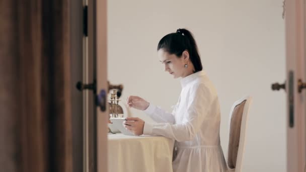 Woman using tablet and drinking coffee by table — Stock Video