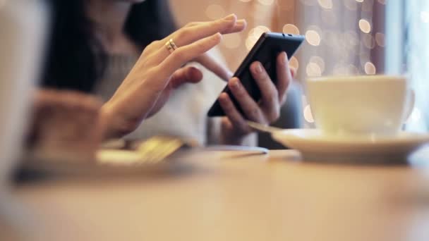 Las manos de la mujer mensajes de texto, utilizando el teléfono inteligente en la cafetería . — Vídeos de Stock