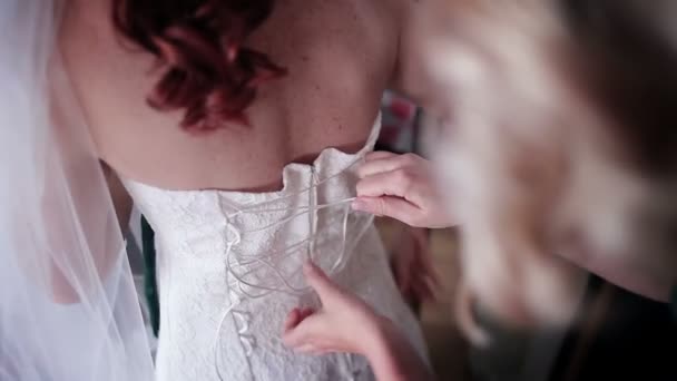 Bruidsmeisjes dichtknopen op trouwjurk — Stockvideo