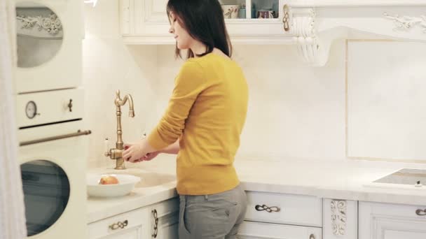 Hermosa chica lava las manzanas en la cocina — Vídeo de stock