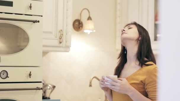 Krásná mladá dívka, užívat si kávu v kuchyni — Stock video