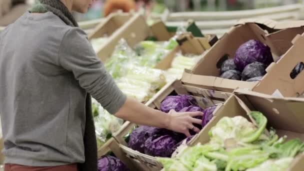 Young woman chooses cabbage on store shelves. — Stock Video