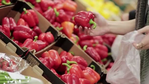 Jonge vrouw kiest paprika op opslagplanken. — Stockvideo