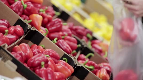 Jonge vrouw kiest paprika op opslagplanken. — Stockvideo