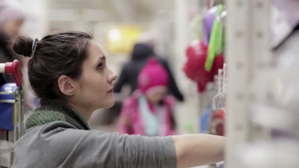 Молода жінка вибирає страви в супермаркеті — стокове відео