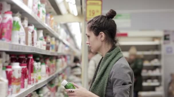 Jonge vrouw kiest voor melk en zuivelproducten in de winkel — Stockvideo