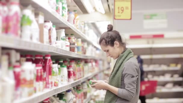 Junge Frau wählt Milchprodukte im Laden — Stockvideo