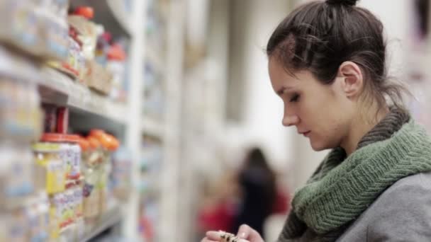 Молода жінка вибирає дитяче харчування в супермаркеті — стокове відео