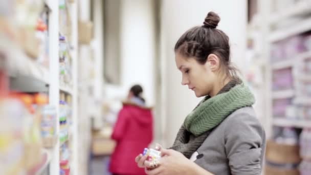 Jonge vrouw kiest babyvoeding in de supermarkt — Stockvideo