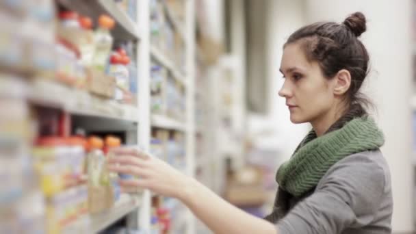 Wanita muda memilih makanan bayi di supermarket — Stok Video