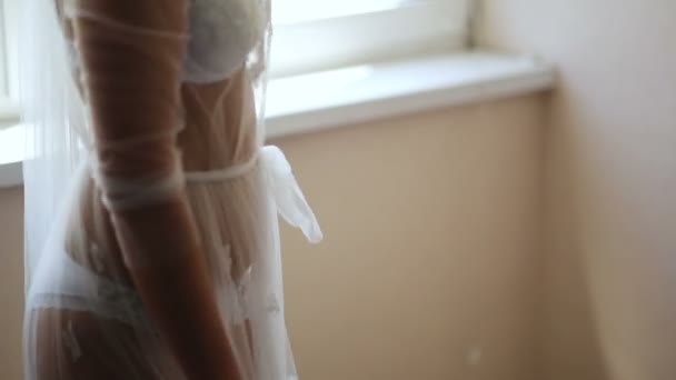 Chica en un hermoso peignoir blanco en la ventana — Vídeo de stock