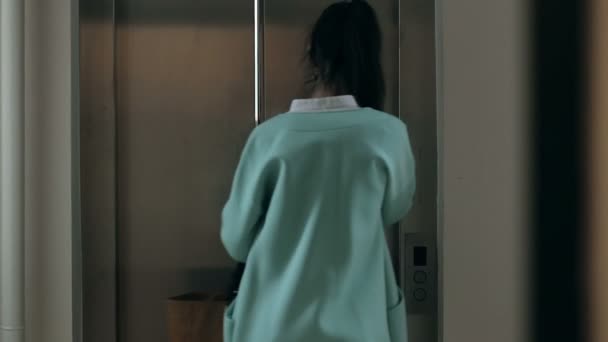 Женщина разговаривает по телефону и входит в лифт — стоковое видео