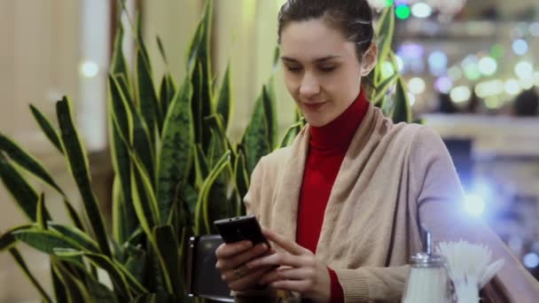使用智能手机，在咖啡馆里喝咖啡的女人. — 图库视频影像