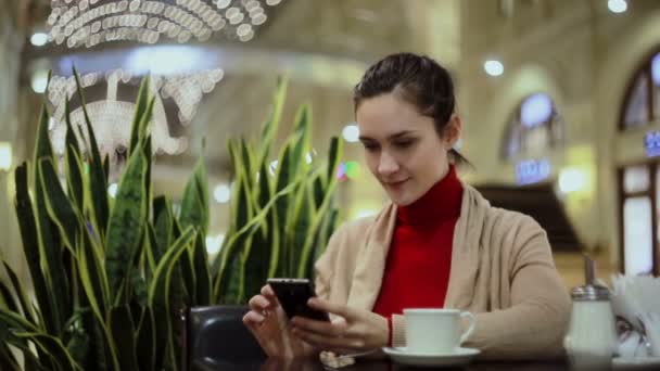 Mulher usando smartphone, beber café no café . — Vídeo de Stock