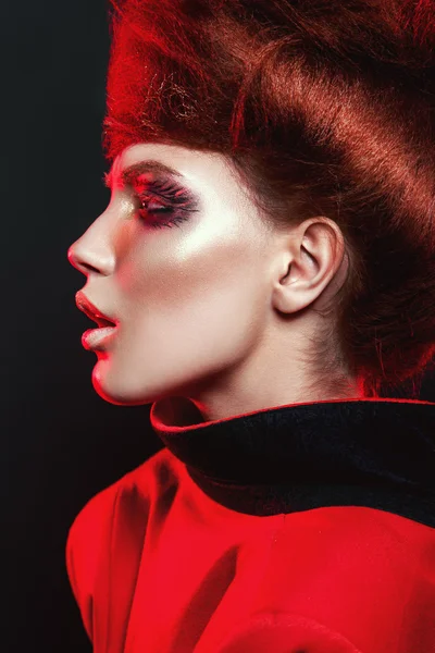 Гаряча дівчина в червоному з креативним макіяжем на чорному тлі — стокове фото