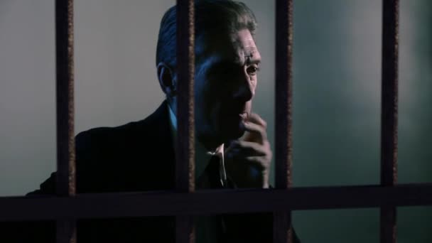 Ein erwachsener Mann sitzt hinter Gittern und geht durch — Stockvideo