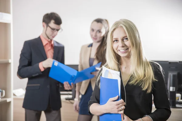 Uma menina estudante sorrindo no fundo de jovens empresários no escritório — Fotografia de Stock