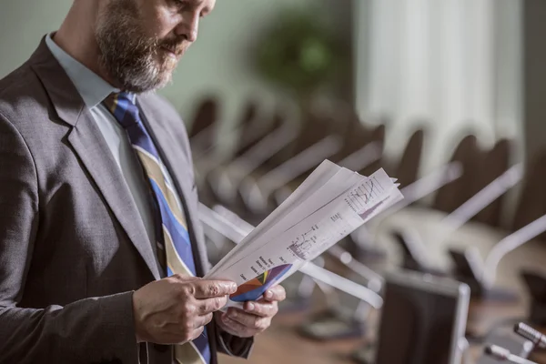 Hombre de negocios barbudo leyendo documentos de negocios con gráficos — Foto de Stock