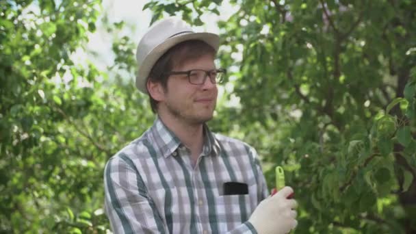 En ung manlig jordbrukare hålla en kratta och leende i trädgården — Stockvideo