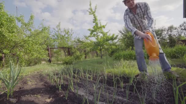 급수 깡통에서 식물을 급수 하는 정원에서 젊은 남자 — 비디오