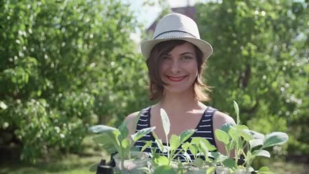 Eine junge Frau hält im Garten viele Triebe von Setzlingen in den Händen — Stockvideo