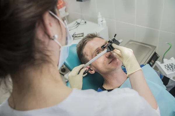 Dentista médico pone en el arco frontal dental paciente. el dentista está en el consultorio junto a la silla con el paciente — Foto de Stock