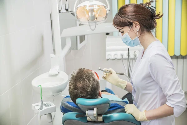 Dental care concept stomatology inspection. the patient lies in a chair in dentistry in front of him a hand with drill — Stock Photo, Image