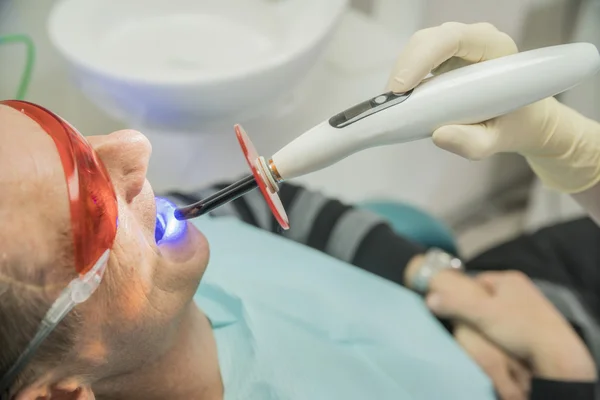 Badanie pacjenta w stomatologii przy użyciu lampy fotopolimeryzacji — Zdjęcie stockowe