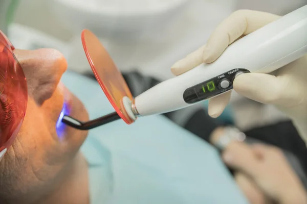 Examen del paciente en odontología mediante una lámpara de fotopolimerización — Foto de Stock