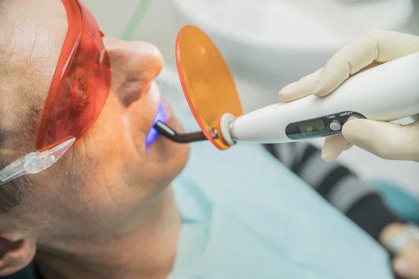 Examen del paciente en odontología mediante una lámpara de fotopolimerización — Foto de Stock