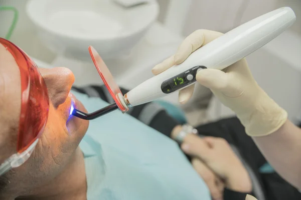 Badanie pacjenta w stomatologii przy użyciu lampy fotopolimeryzacji — Zdjęcie stockowe