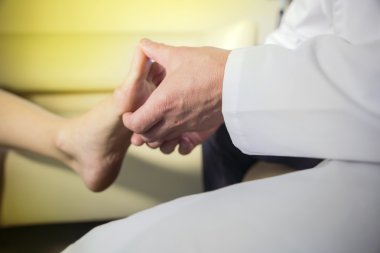 Doktor elinde bir hastanın ayak inceliyor