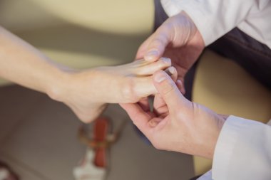 the hands of the doctor examines the foot of a patient clipart