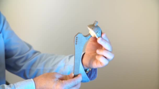 医師の手で人工股関節のクローズ アップ、彼は人工関節の操作の原理を示しています — ストック動画