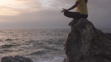 Yoga yapan kadın Lotus pozisyonunda yoga ve meditasyon yapıyor. Akşam okyanusunda açık havada