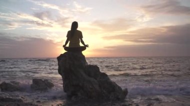 Yoga yapan kadın Lotus pozisyonunda yoga ve meditasyon yapıyor. Akşam okyanusunda açık havada