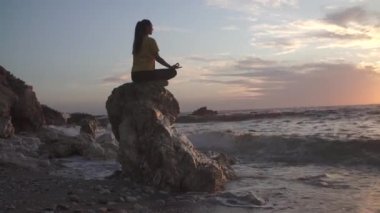 Yoga yapan kadın Lotus pozisyonunda yoga ve meditasyon yapıyor. Akşam okyanusunda açık havada