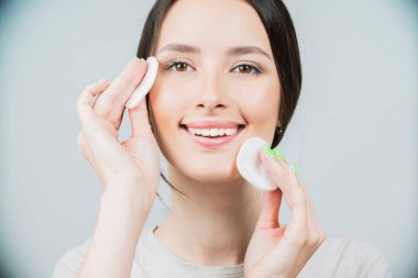 Süngeri olan güzel esmer bir kadın, temiz, taze bir cilt pamuk pedi kullanıyor. Bir beyazda izole edilmiş.