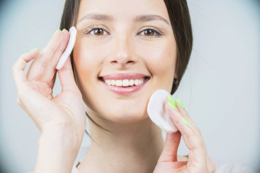 Süngeri olan güzel esmer bir kadın, temiz, taze bir cilt pamuk pedi kullanıyor. Bir beyazda izole edilmiş.