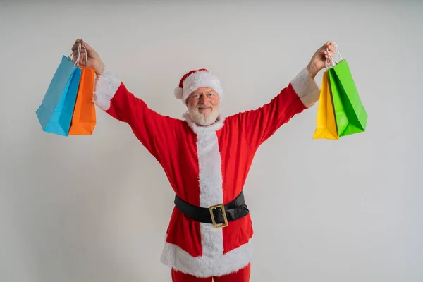 白髪染めサンタさんが白い背景にクリスマスバッグを持って買い物に行き クリスマスギフトバッグを持っています — ストック写真