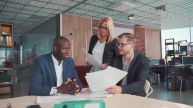 Modern bir ofiste üç işadamı, genç bir adam, Afrikalı bir işadamı ve bir kadın.