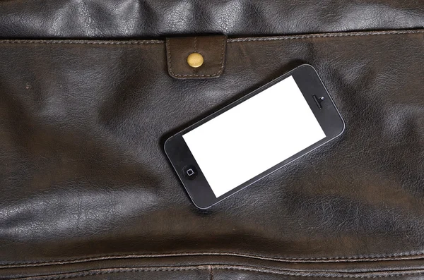 Mobiltelefon liggande på en läderväska Royaltyfria Stockbilder