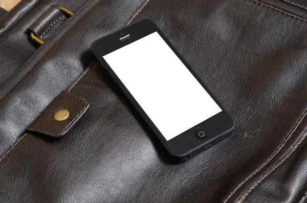 Mobiltelefon liggande på en läderväska Royaltyfria Stockfoton