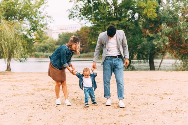 Family walking and having a great time together on sand in park near a lake — Stock Photo, Image