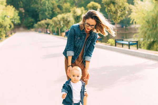 A young woman and her baby walking in the park — Stock Photo, Image