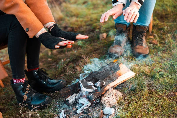 Two women are warming up near a burning wood on a field — Stock Photo, Image
