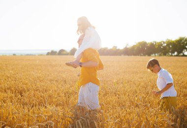 Baba çocuklarıyla güneşli bir günde buğday tarlasında vakit geçiriyor.