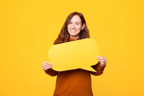 Mujer joven está sonriendo y mirando a la cámara está sosteniendo una burbuja de habla — Foto de Stock