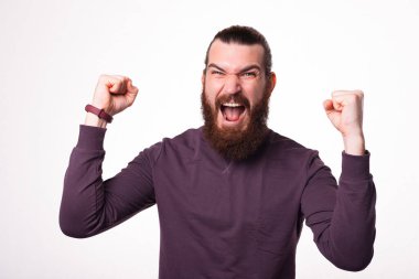 Sakallı adam kameraya bakıyor ve iki eli havada bağırıyor çünkü kazandı.