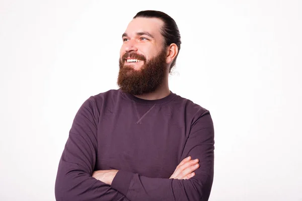 Retrato de un hombre barbudo sentado con los brazos cruzados y mirando hacia otro lado sonriendo — Foto de Stock